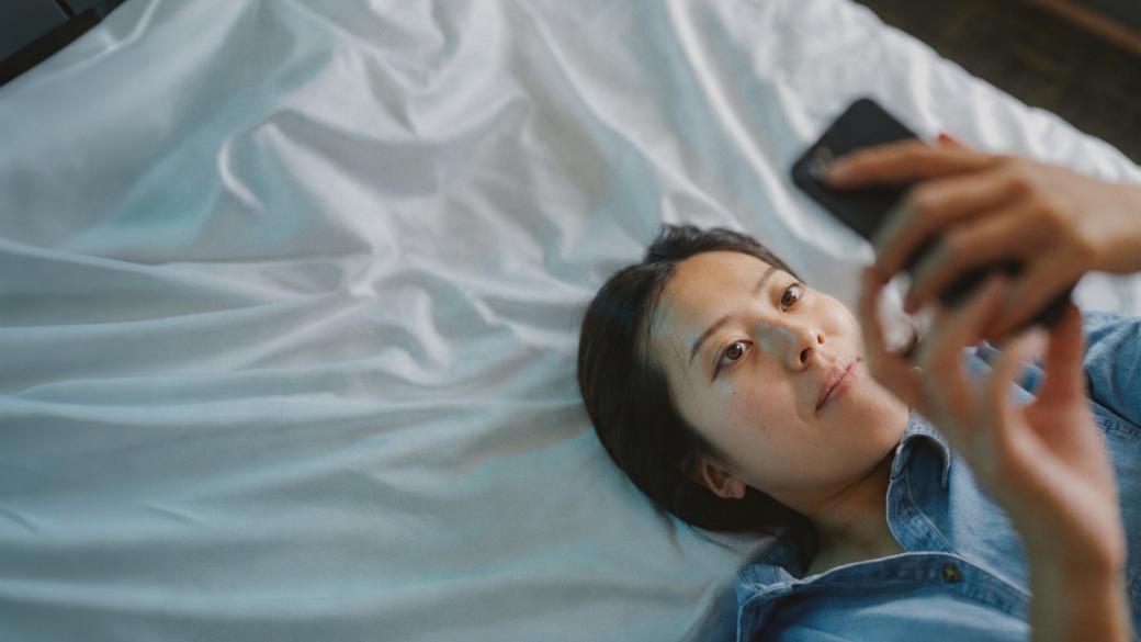 Person lying on a bed using a smartphone to access TSB mobile banking app