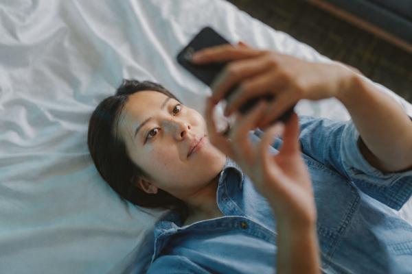 Person lying on a bed using a smartphone to access TSB mobile banking app