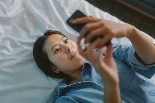Person lying on a bed using a smartphone to access TSB mobile banking app