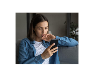 Woman sitting on a couch looking concerned at her smartphone