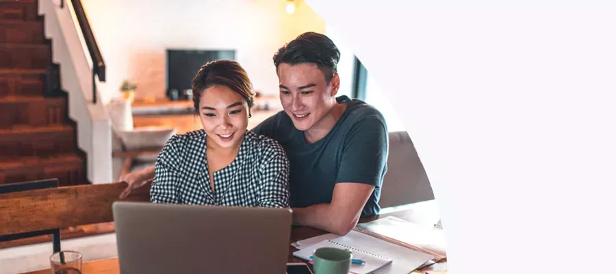 young couple sitting at table exploring term investments on their laptop