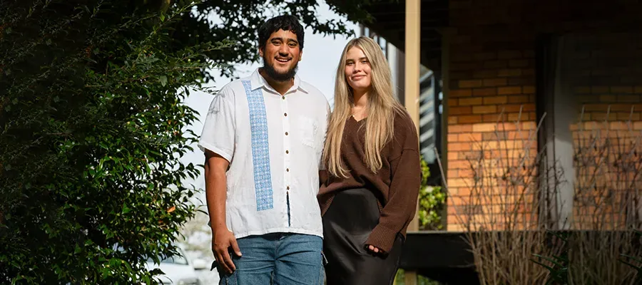 married couple standing in front of their house