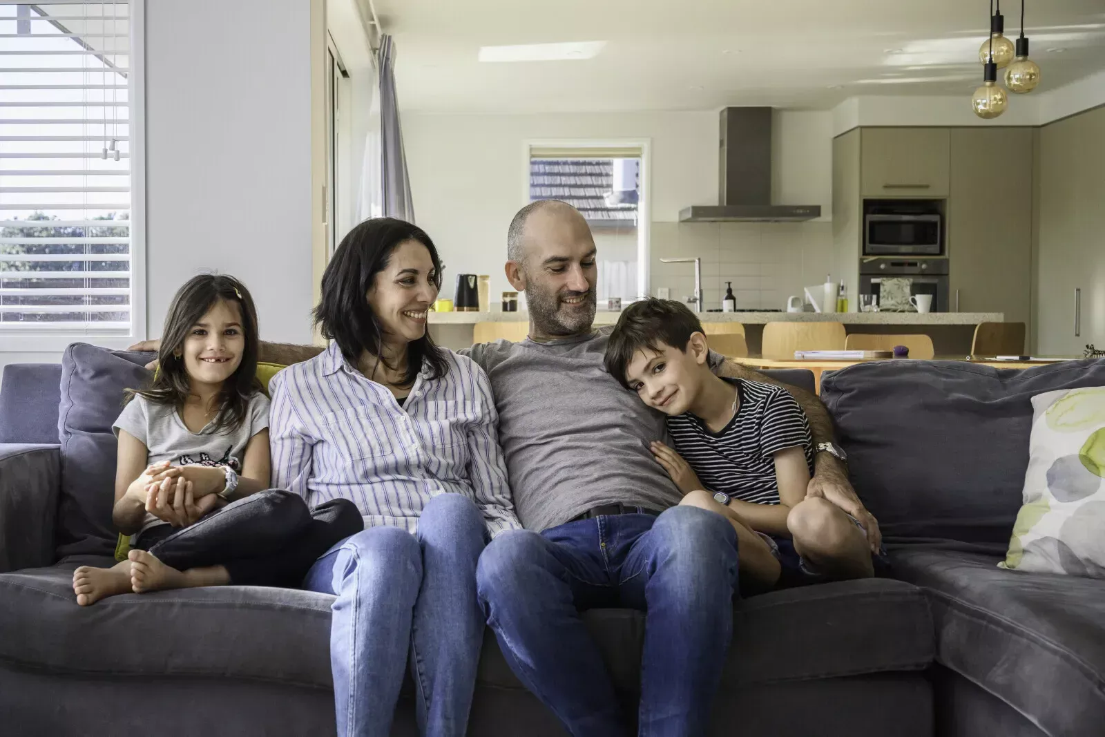 family sitting on couch together smiling