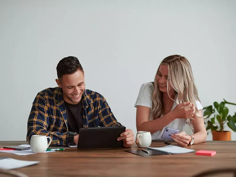Young couple sitting at the table looking at their laptop and smartphone