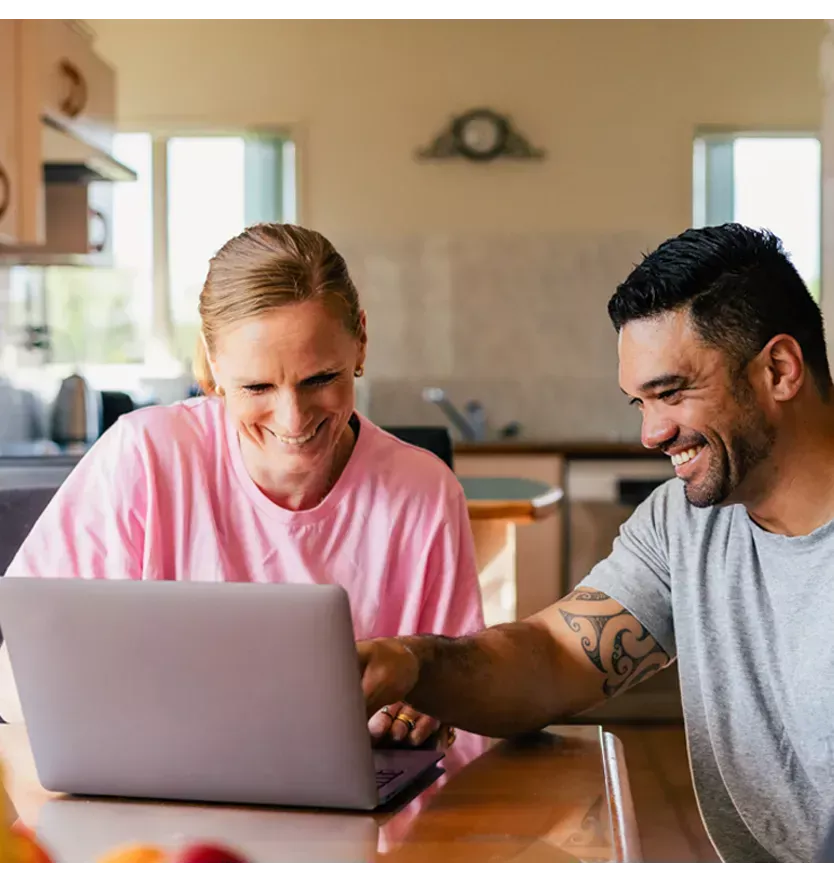 Man & woman with laptop in the kitchen looking at their finances