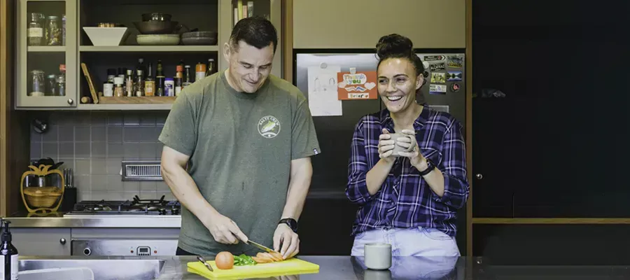 couple at kitchen bench cooking dinner and talking