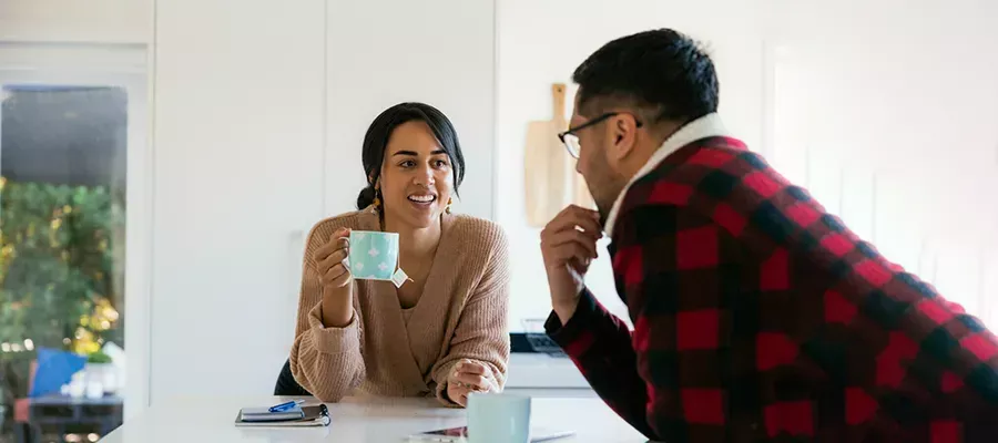 parents having a coffee in kitchen leaning over bench chatting