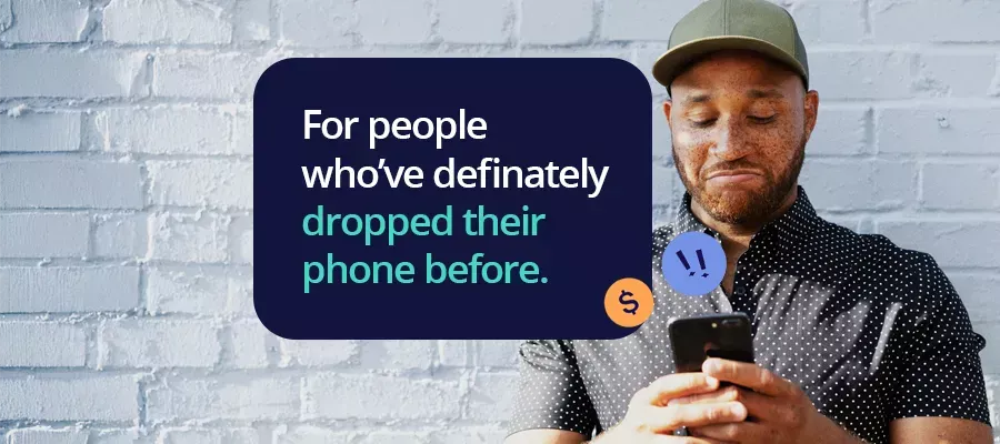 Man looking down at his phone against brick wall