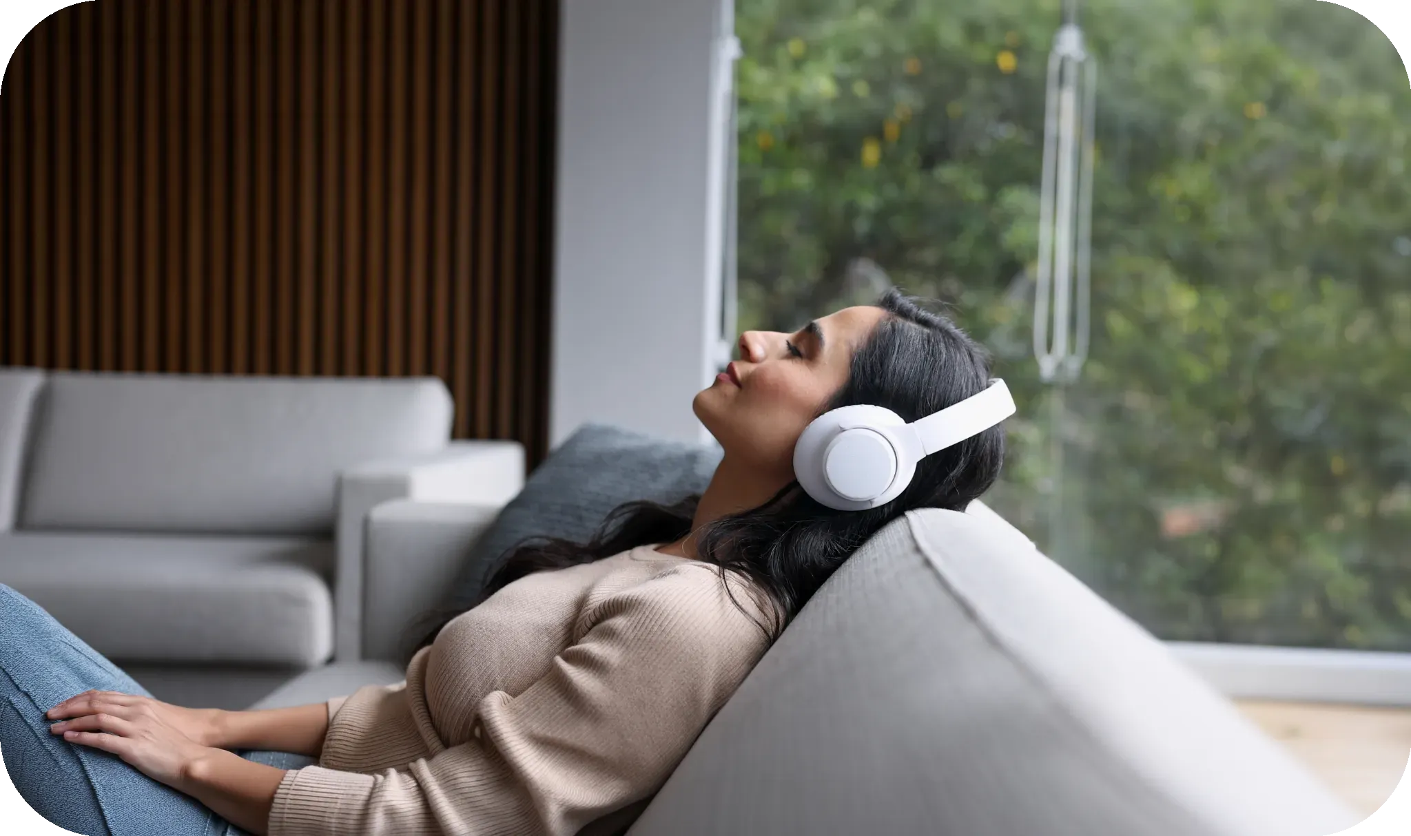 Relaxing on a sofa wearing headphones.