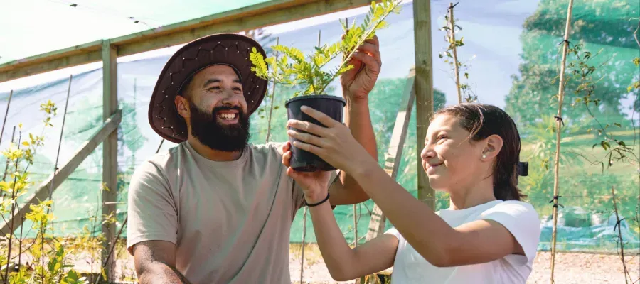 People holding a small plant to represent long-term savings and KiwiSaver