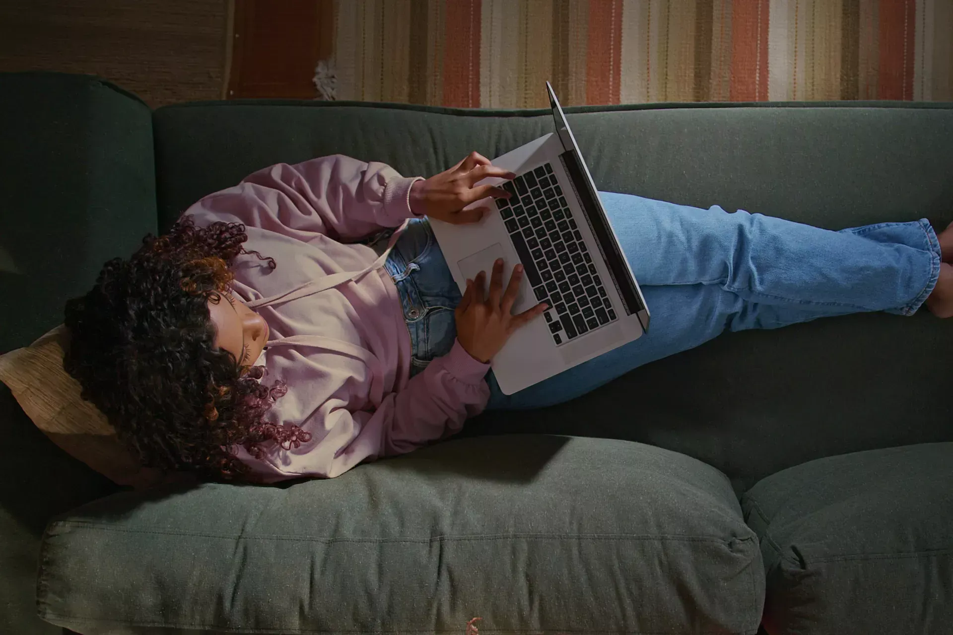Person using a laptop while lying on a couch at home, representing TSB everyday online banking