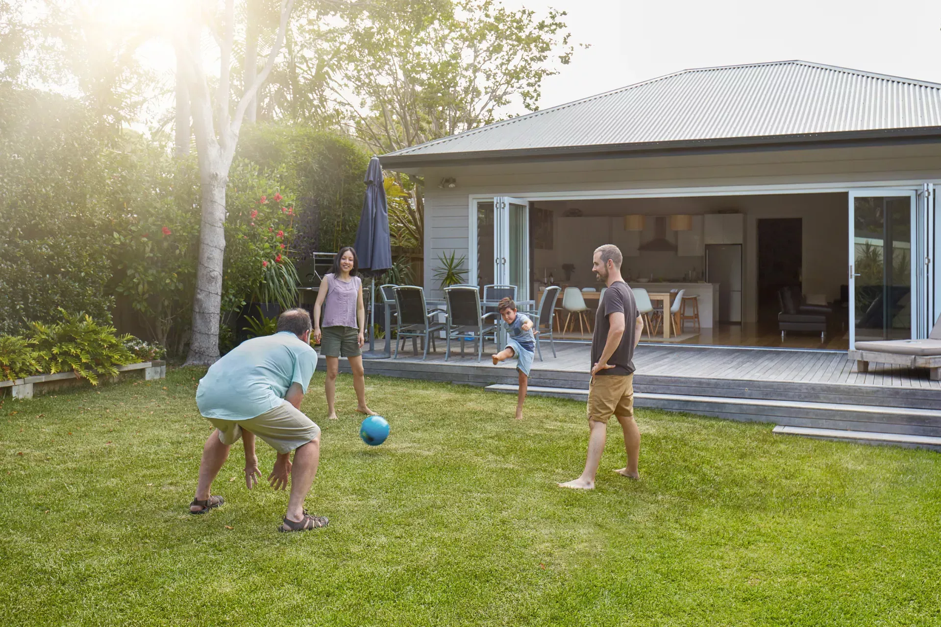 Family playing with a ball outside a home, representing home ownership