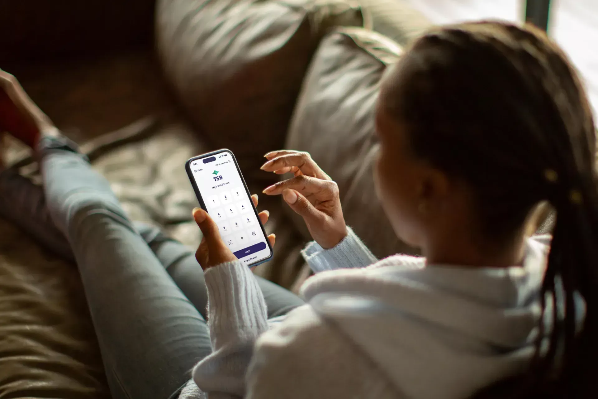 person relaxing on the sofa looking at mobile banking app